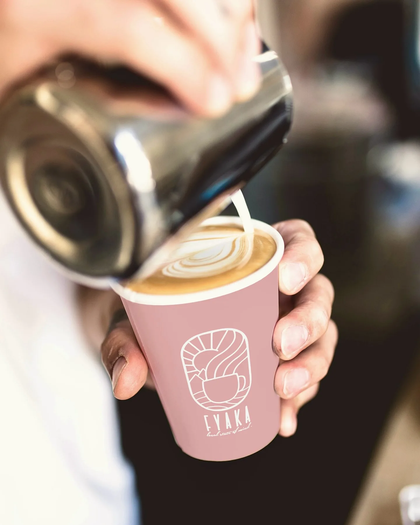 Latte art being poured into a pink Fyaka cup