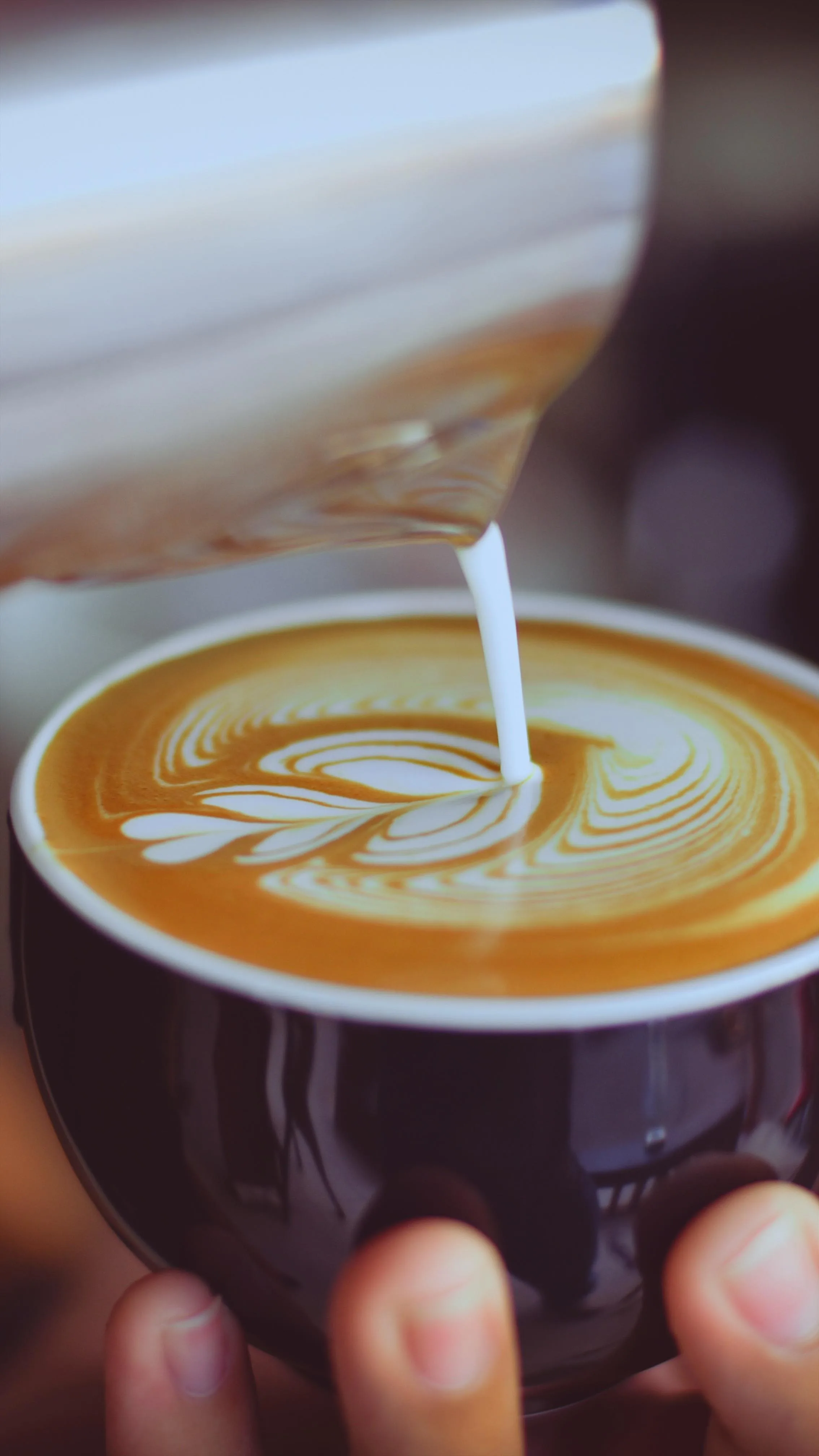 Latte art being poured into a coffee cup